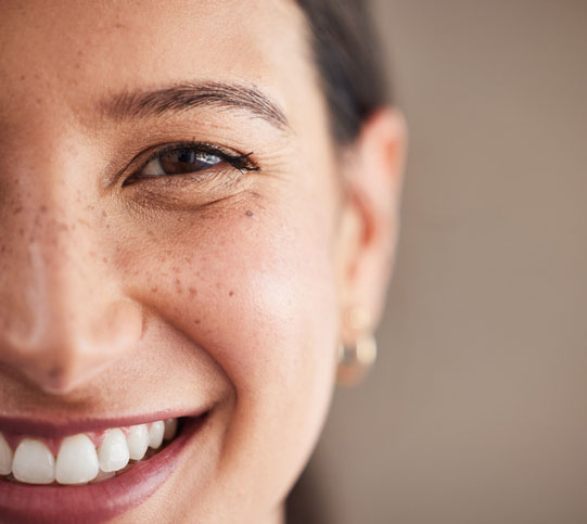 Face of beautiful mixed race woman smiling with white teeth.  Portrait of a woman's face with brown eyes and freckles posing with copy-space